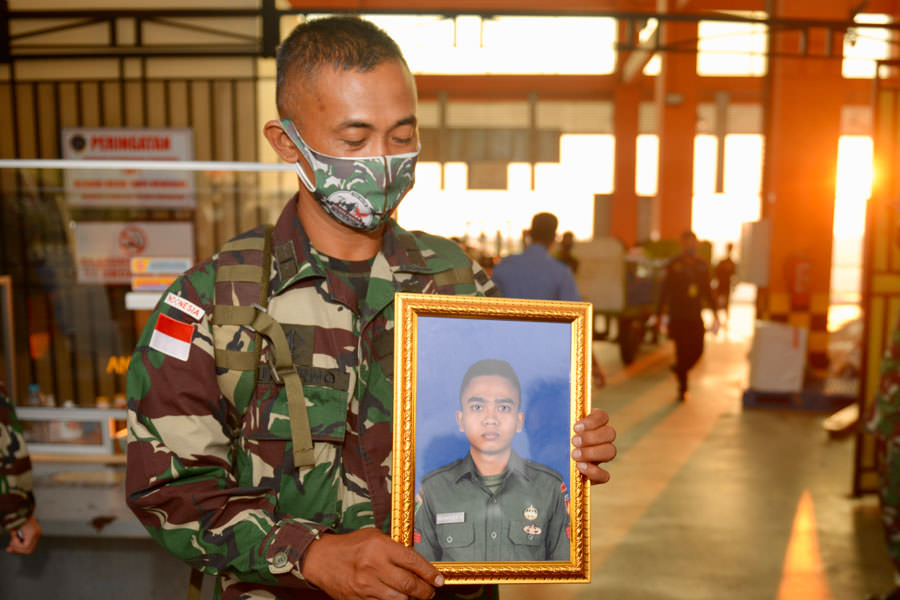 Seorang anggota TNI Kodam XII Tanjungpura memegang foto alm Pratu Ida Bagus Putu Suwarman, saat menyambut kedatangan peti jenazah di Kargo Bandara Internasional Supadi Pontianak, Rabu (22/9) petang. Pratu Ida Bagus Putu Suwarman gugur dalam tugas di perba