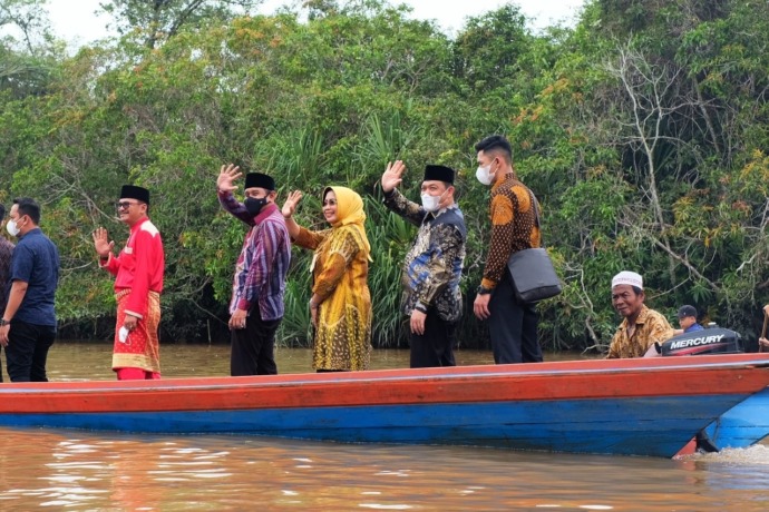 NAIK PERAHU : Wagub beserta istri yang juga Bupati Mempawah, Erlina, menaiki perahu saat mengunjungi desa Gelik Kabupaten Sambas. (IST)