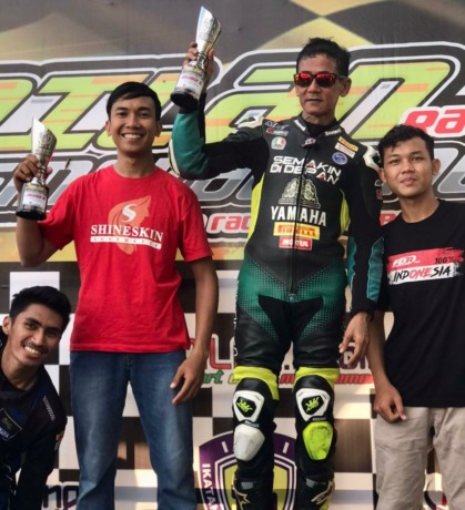 Syarif Machmud Alkadrie saat berdiri di atas podium dalam penyerahan piala juara I kelas sport 250cc pada ajang balap motor Dilan Racing Singkawang, Minggu (6/2). (Istimewa)
