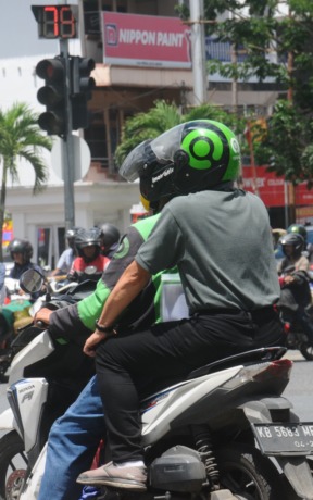 KEMUDAHAN AKSES: Warga menggunakan ojek online saat berhenti di lampu merah Jalan Tanjungpura. Adanya layanan ojek online cukup mempermudah masyarakat dalam memilih akses transportasi. (HARYADI/PONTIANAKPOST)