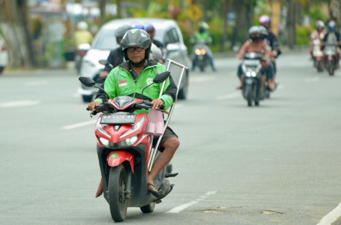 ANTAR ORDERAN: Odos Yunus, seorang driver ojek online penyandang disabilitas saat mengantarkan orderan kepada pelanggannya di Kota Pontianak, Sabtu (10/9). (ARIEF NUGROHO/PONTIANAK POST) 