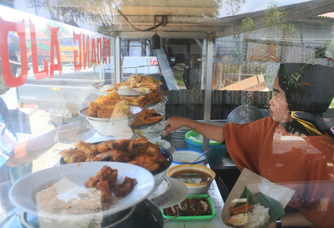 LAYANI PEMBELI: Pelayan Rumah Makan Padang Ajo melayani membeli yang memesan makanan. IST