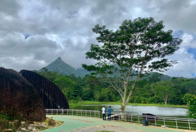 Wisatawan menikmati pemandangan Batu Belimbing di tengah danau dengan latar belakang pegunungan di Singkawang Timur. foto Shando Safela