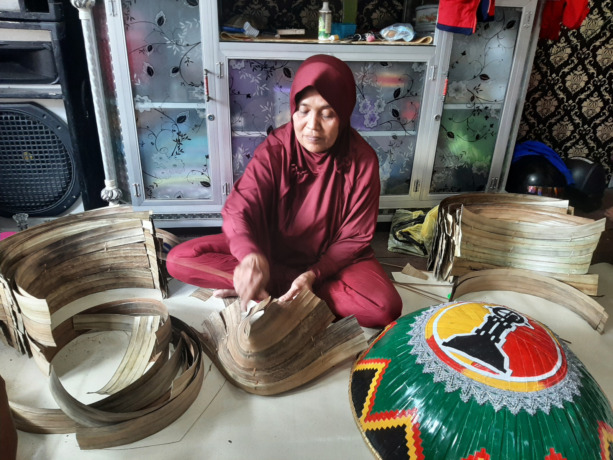 Mak Midot, seorang perajin caping Kampung Mendawai sedang menyemit daun mengkuang untuk dijadikan topin caping. (Syahriani/Pontianak Post)