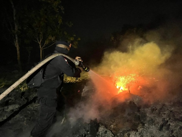 PADAMKAN API: Seorang anggota Brimob sedang memadamkan kebakaran lahan di desa Punggur Kecil, Kubu Raya, Kamis malam (10/8). (IST)
