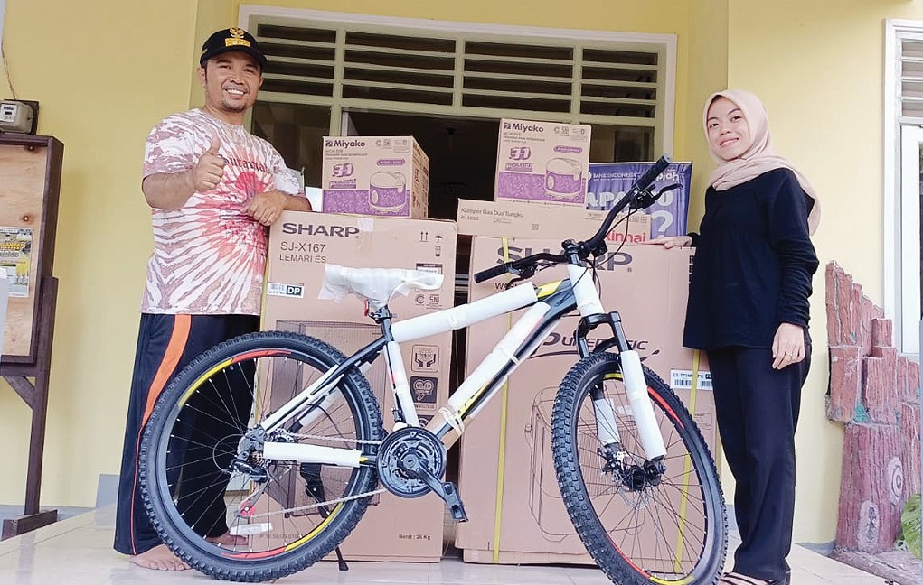 HADIAH : Lurah Pejarakan Karya Mulhakim SH bersama pengurus  Karang Taruna Pejarakan Karya  Dwi Ayu berpose bersama hadiah jalan sehat di depan Kantor Lurah Pejarakan Karya, Kecamatan Ampenan kemarin