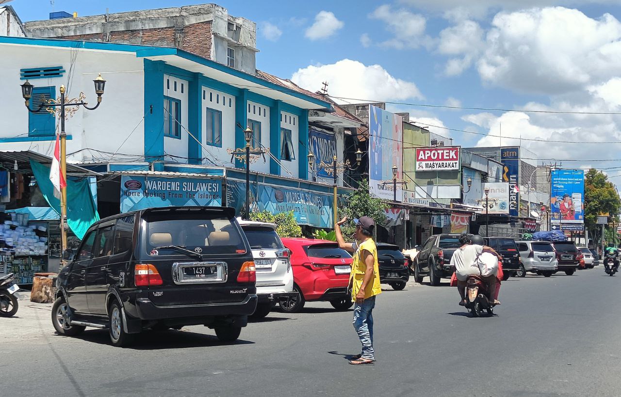 Seorang juru parkir tengah mengatur lalu lintas di kawasan Cakranegara.