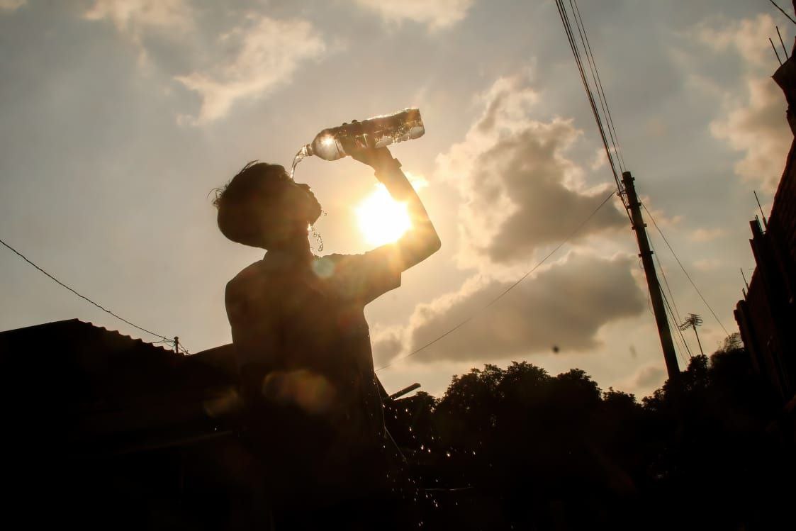 Seorang warga membasuh kepalanya dengan air, mengurangi rasa panas akibat suhu udara yang meningkat.