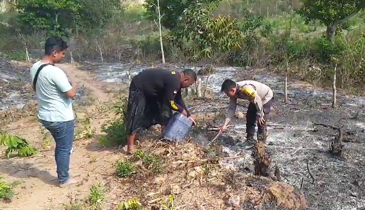 Personel Polsek Kawasan Mandalika bersama warga memadamkan api di lahan warga.