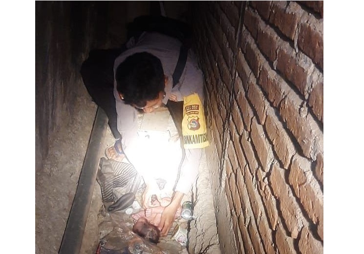 BAYI DIBUANG: Seorang anggota Polsek Lambu mengambil bayi yang dibuang di parit, beberapa hari lalu.(POLSEK LAMBU FOR LOMBOK POST)