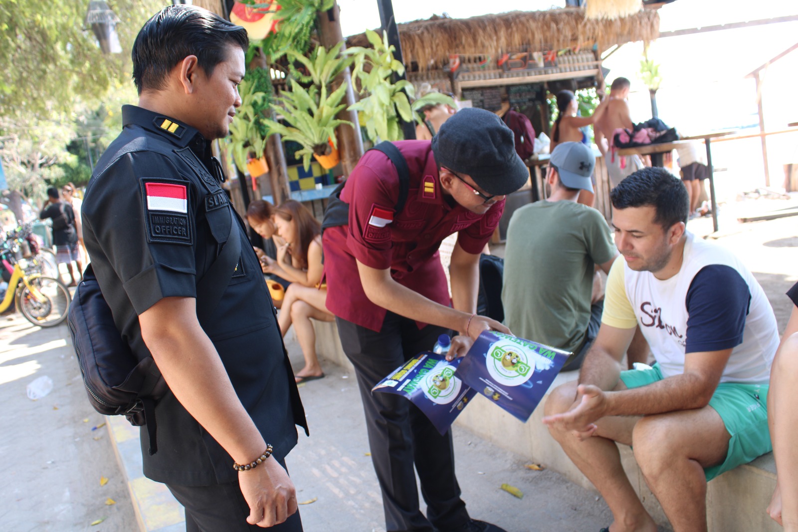 Petugas Imigrasi Mataram membagikan brosur  Si Rambo Jawara Nekat, inovasi informasi layanan keimigrasian di Gili Trawangan, Jumat (27/9).