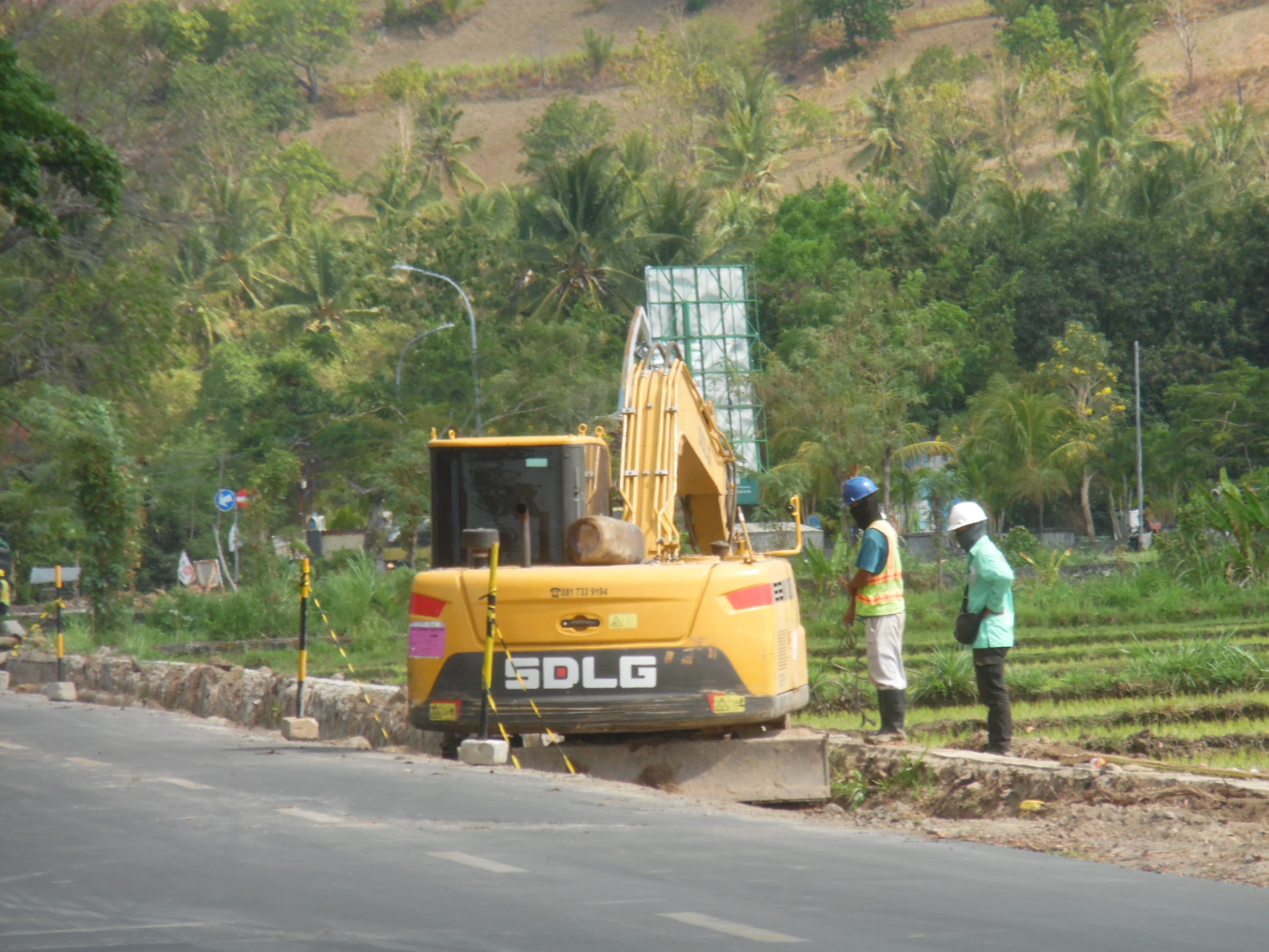PELEBARAN JALAN: Dua pekerja sedang proses keruk jalan untuk dilebarkan di Kecamatan Gangga, Lombok Utara, beberapa waktu lalu.(NURUL/LOMBOK POST)