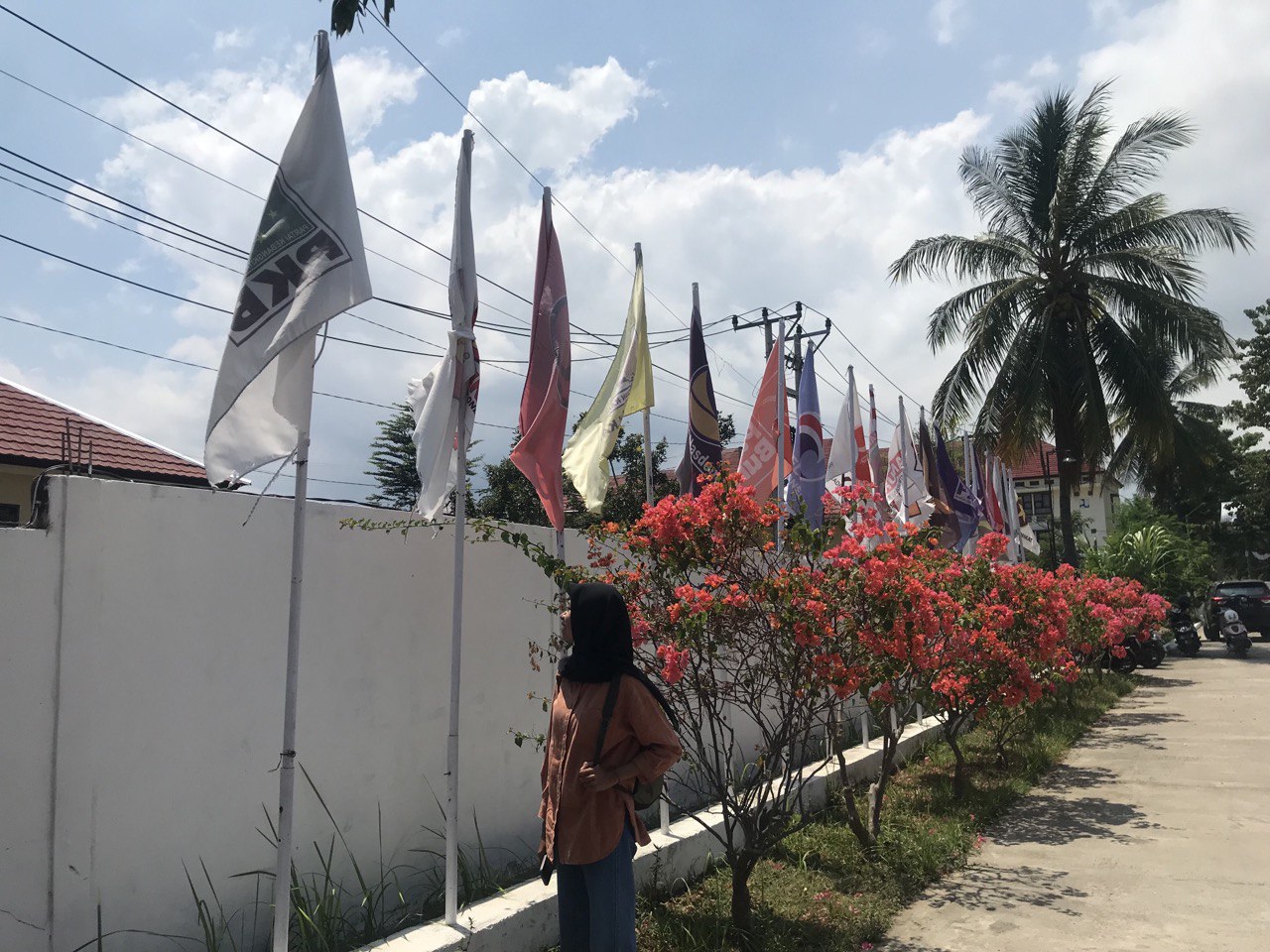 PILIH-PILIH: Seorang pemilih wanita KLU sedang melihat beberapa bendera parpol peserta pemilu 2024 KLU di Kantor KPU Lombok Utara, belum lama ini.(NURUL/LOMBOK POST)