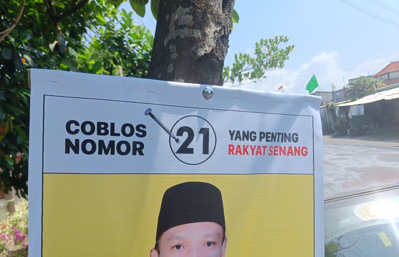 Poster salah seorang kontestan pemilu yang terpasang dengan dipaku di pohon dekat pasar Pagutan, Kota Mataram.