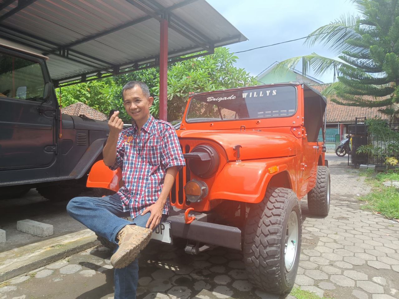 Chris Parangan duduk di salah satu koleksi mobil Jeep miliknya.