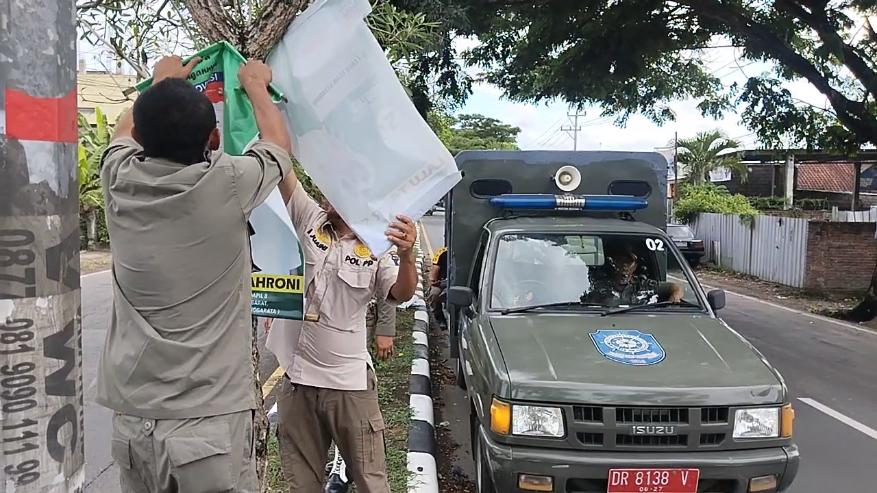 LANGGAR ATURAN: Petugas Satpol PP Loteng mencopot ratusan alat peraga kampanye yang terpasang di median jalan protokol Kota Praya, Kamis (30/11).