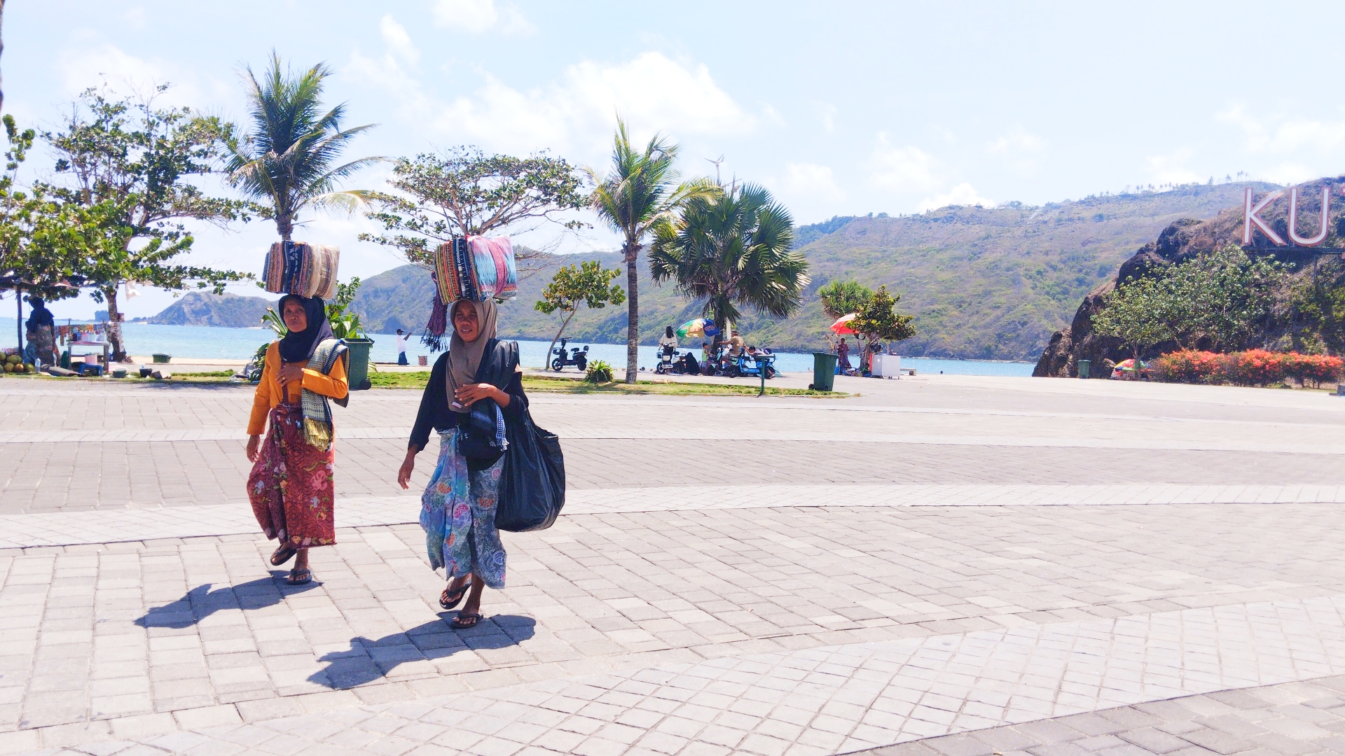 HARUS DIPROMOSIKAN: Dua orang pedagang kain khas Lombok melintas disekitar area Kuta Beach Park Mandalika, Loteng, beberapa waktu lalu.