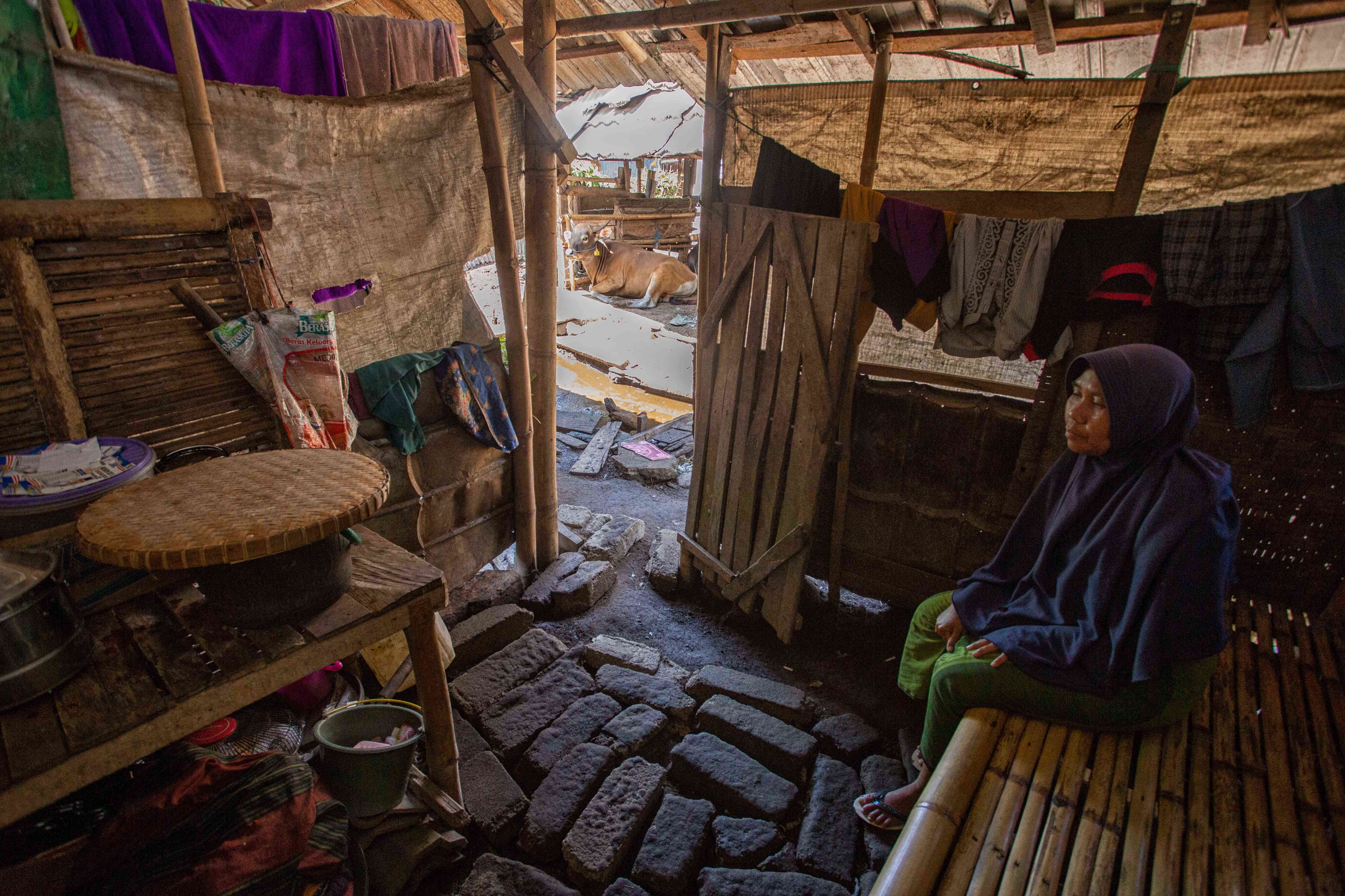 BUTUH BANTUAN: Nurjanah duduk di rumahnya yang dibangun di kandang sapi milik orang lain di Desa Karang Bayan, Lombok Barat. Rumah yang dibangun tersebut terbuat dari barang bekas sumbangan warga.