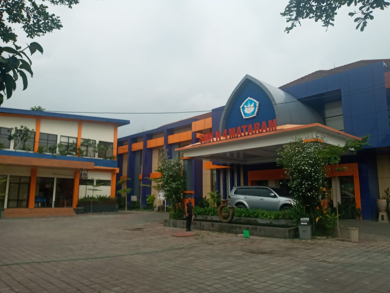 SMK BLUD: Seorang pegawai berdiri di depan lobby SMKN 4 Mataram. (ROJAI/LOMBOK POST)