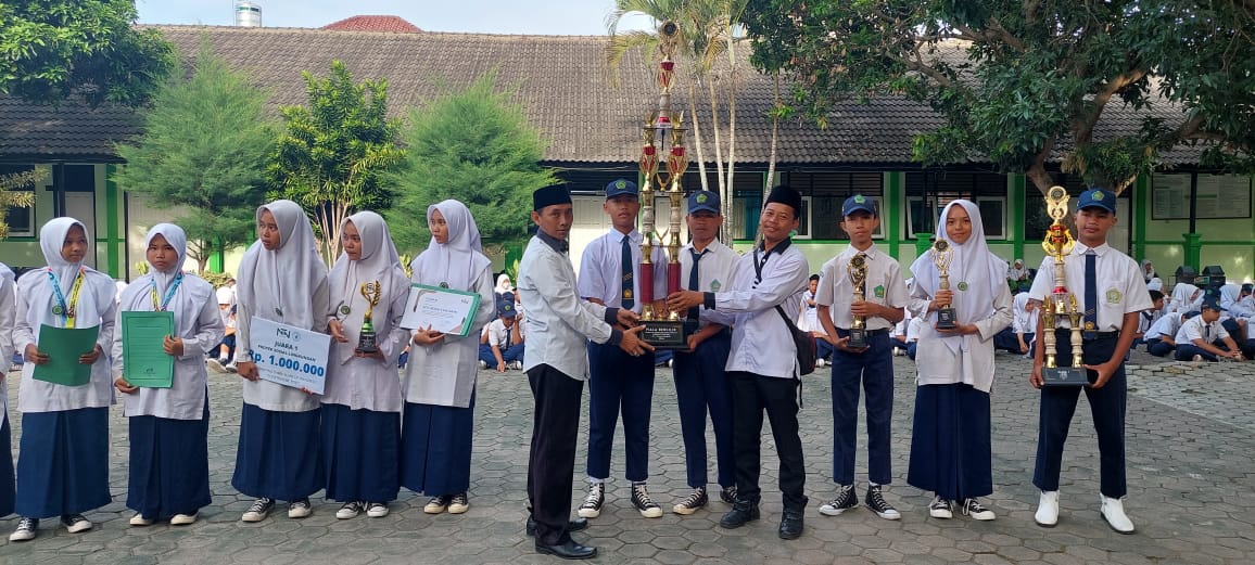 MEMBANGGAKAN: Kepala MTsN 2 Mataram Sumber Hady (kiri) menerima piala  bergilir juara umum LKKB di madrasah setempat, beberapa waktu lalu. (MTSN 2 MATARAM FOR LOMBOK POST)