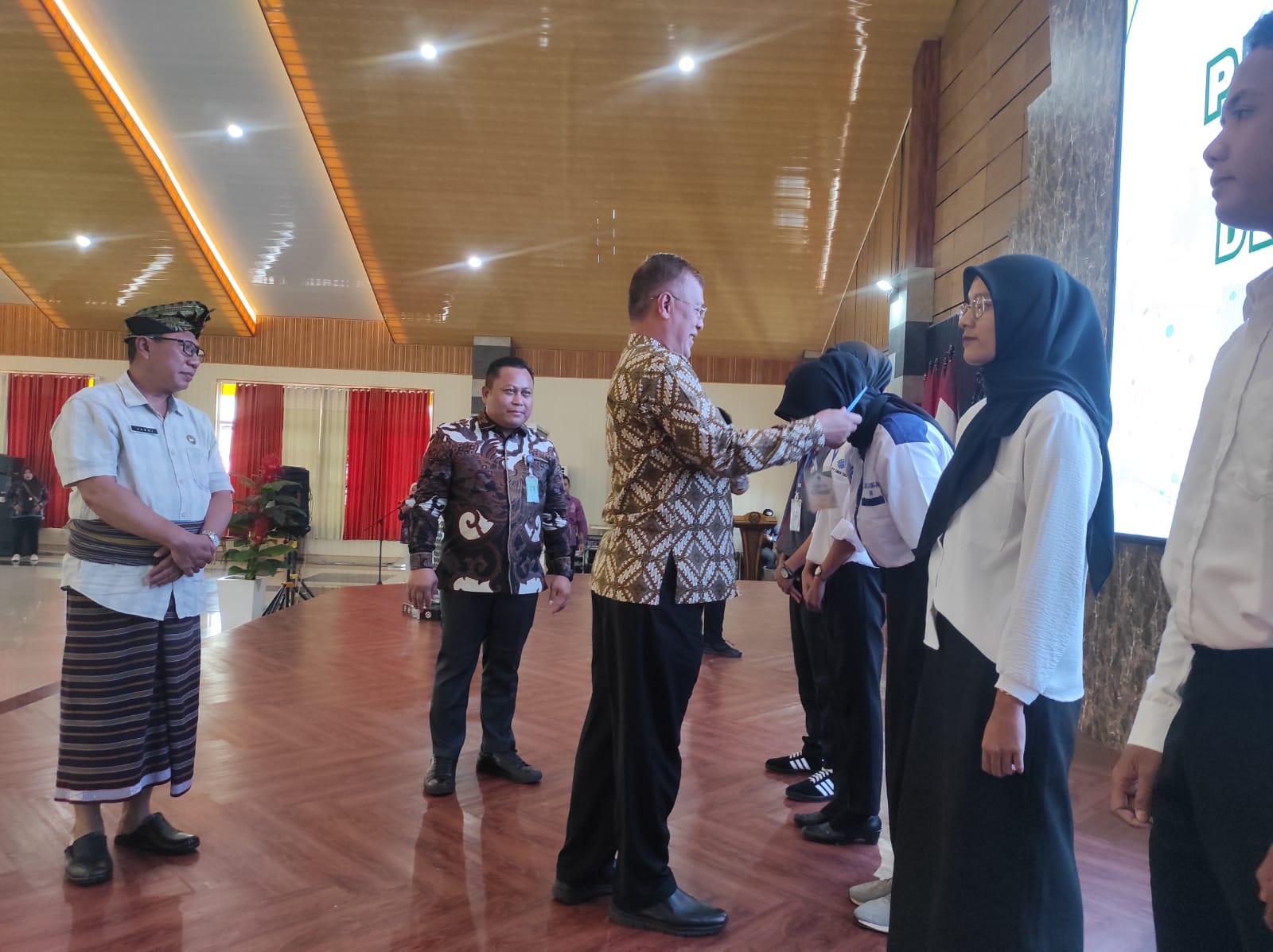 SIMBOLIS: Plt Sekretaris Dirjen Binalavotas Kemenaker RU Muhamad Ali mengalungkan id card ke peserta di Acara Kick Off pelatihan Vokasi BVPV Lotim dengan UPTD binaan, Kamis (1/2).