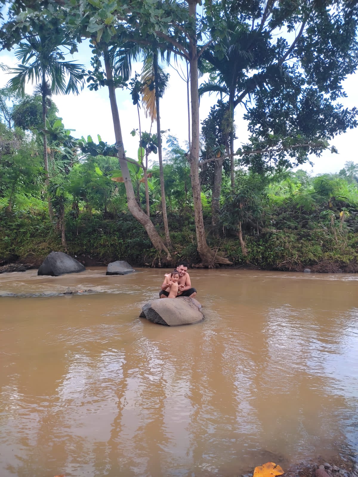 KERUH: Seorang bapak yang sedang mandi dengan anaknya di sungai dengan air keruh akibat proyek Bendungan Meninting. (Foto Istimewa)