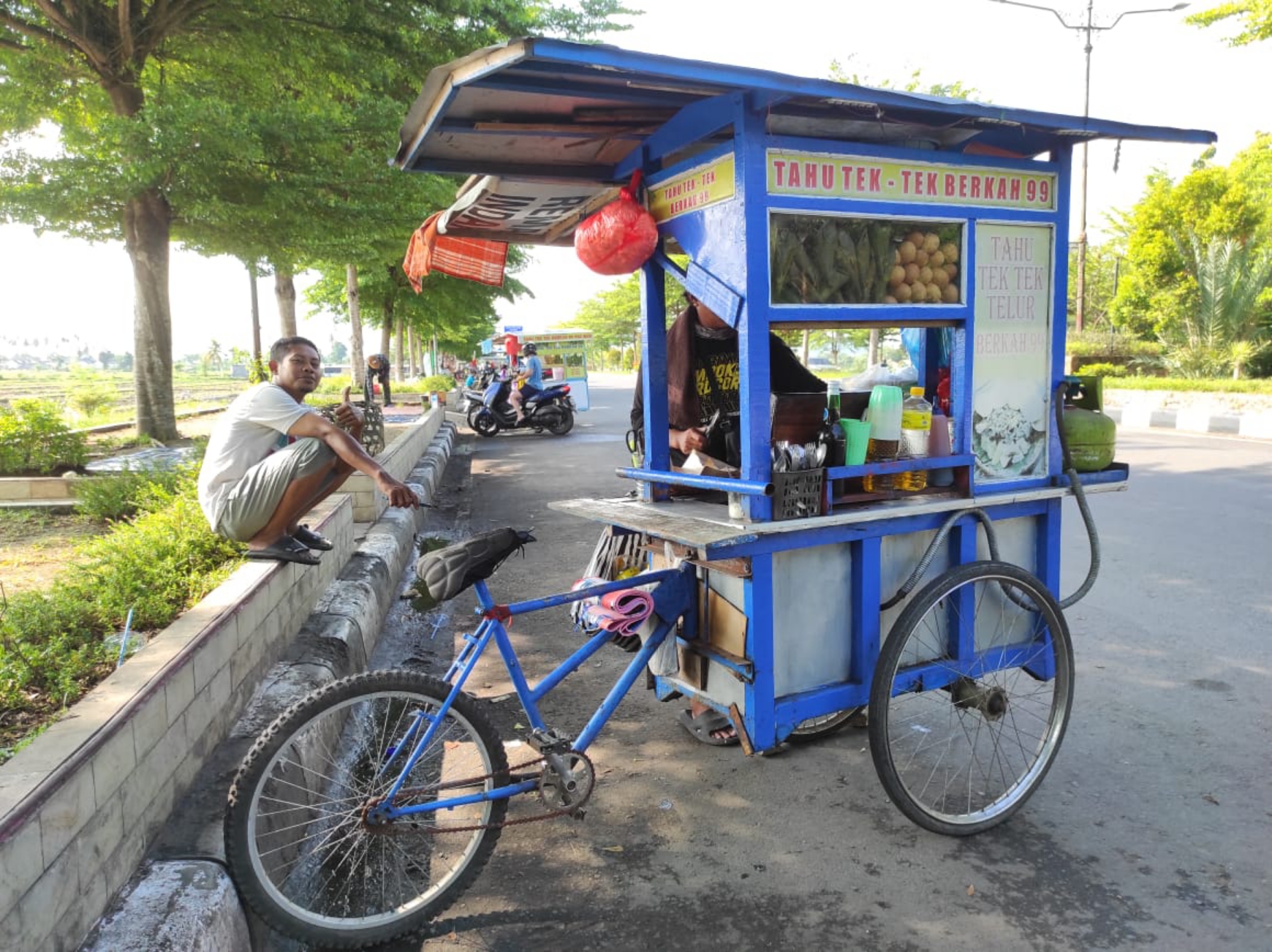 KAKI LIMA: Junaidi, penjual tahu tek yang tengah melayani pembeli di dekat Monumen Tembolak, Bypass Mataram. (FERIAL/LOMBOK POST)