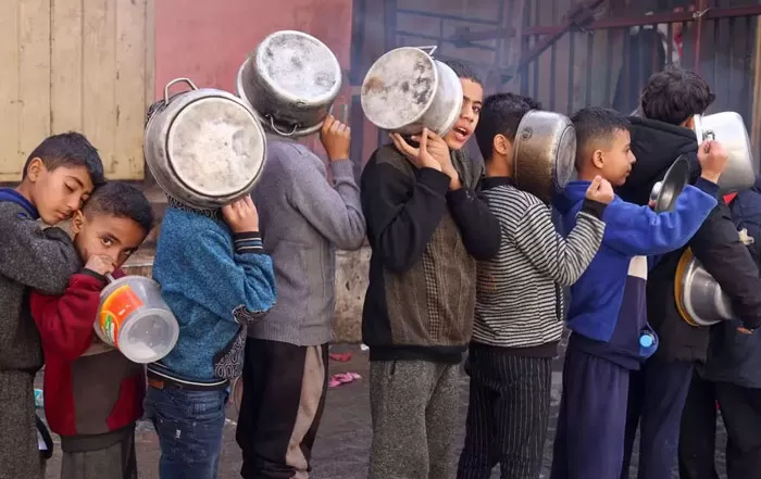 Anak-anak Palestina sedang mengantre makanan dengan panci yang mereka bawa di tengah kekurangan persediaan makanan. (REUTERS/Salah Salem)