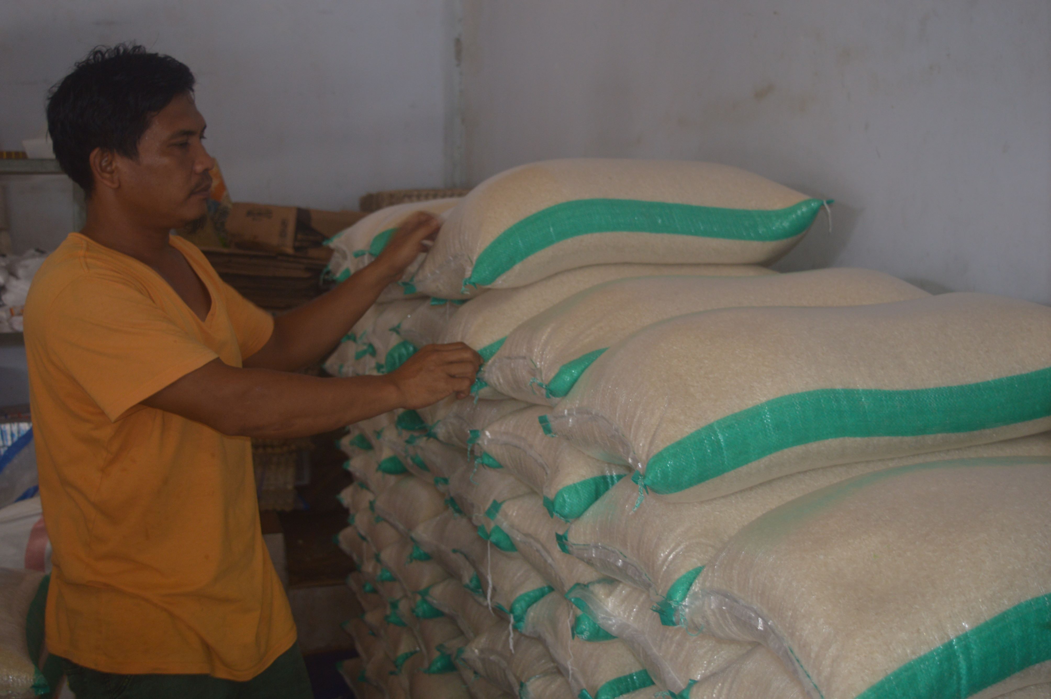 Seorang buruh sedang mengangkut karungan beras ke dalam toko di Pasar Renteng, Praya, Senin (19/2).