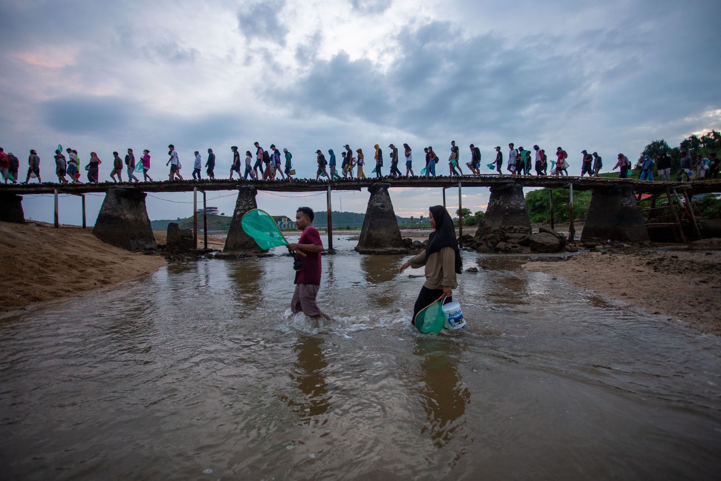 SEGERA DIPERBAIKI: Pengunjung lokal melintasi jembatan Pantai Seger usai menangkap Nyale pada event tahun lalu.