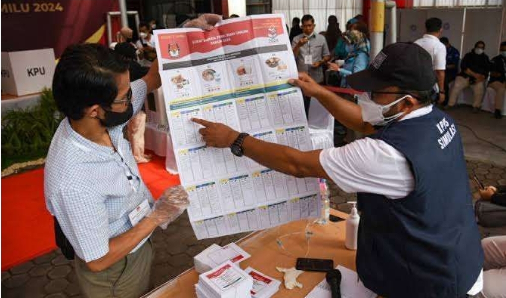 Petugas KPPS saat memberikan petunjuk cara mencoblos kertas suara kepada pemilih pemilu. (Foto: Antara)