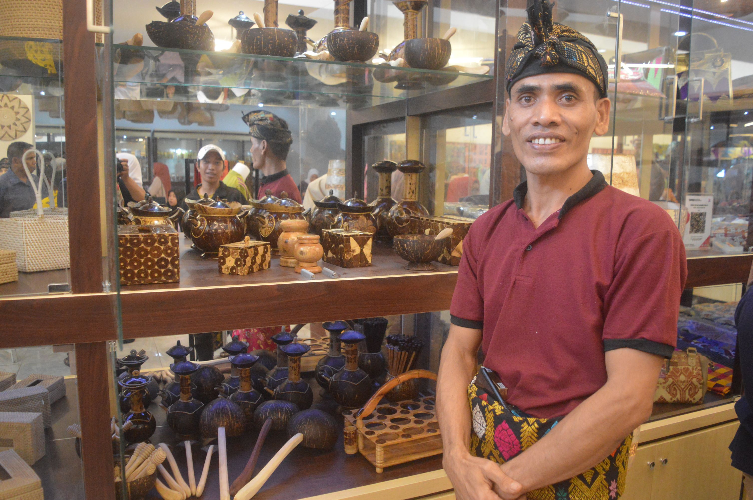 Seorang perajin berfoto di depan lemari pajangan produk miliknya saat dipamerkan di gedung PLUT Loteng, beberapa waktu lalu.