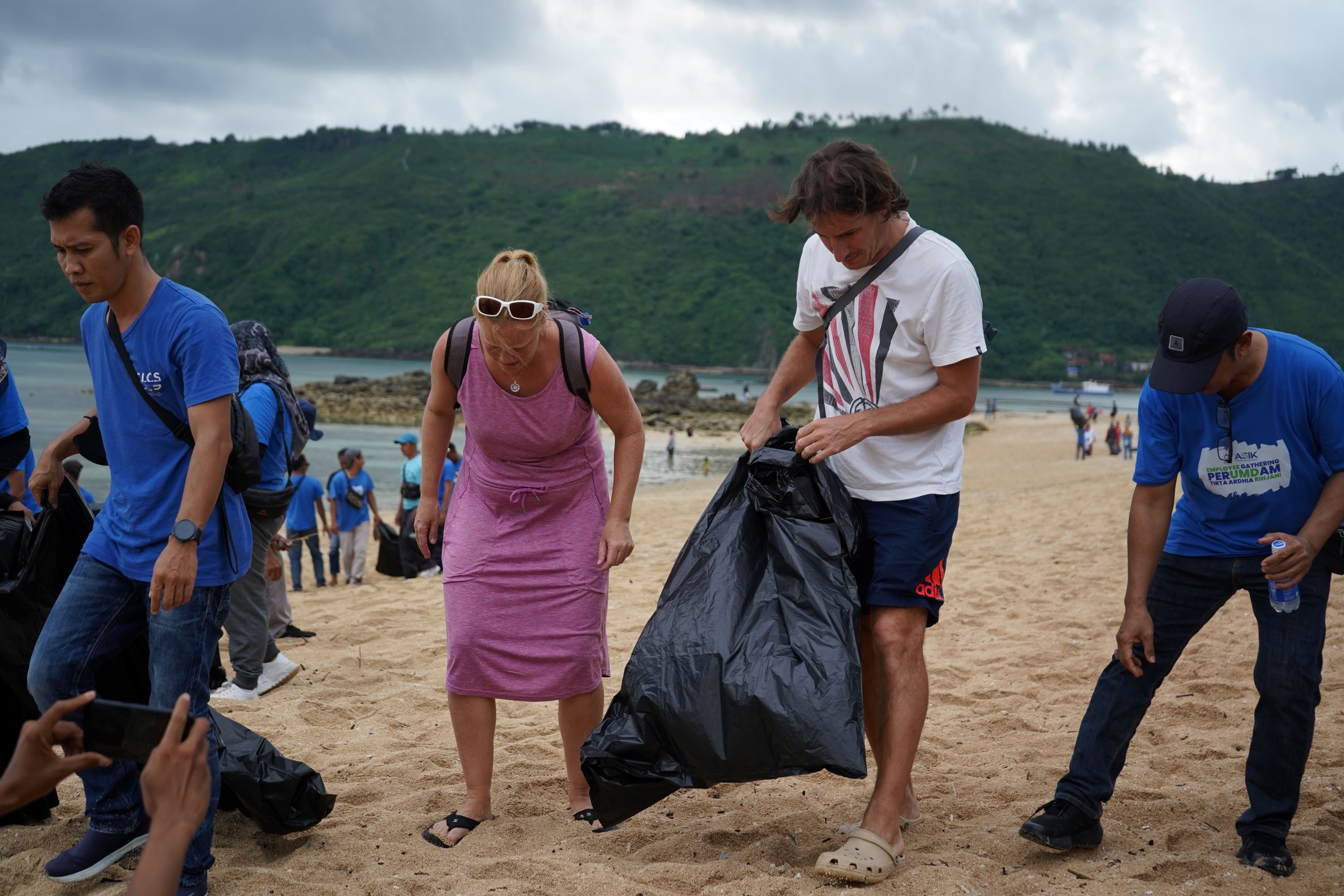 Dua orang wisatawan asing ikut serta memungut sampah di pesisir Pantai Kuta Mandalika dalam suatu acara, belum lama ini.