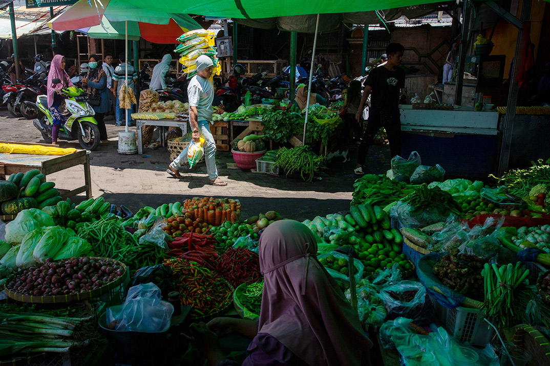 Seorang warga memanggul beras yang dibeli di pasar Kebon Roek, Kota Mataram.