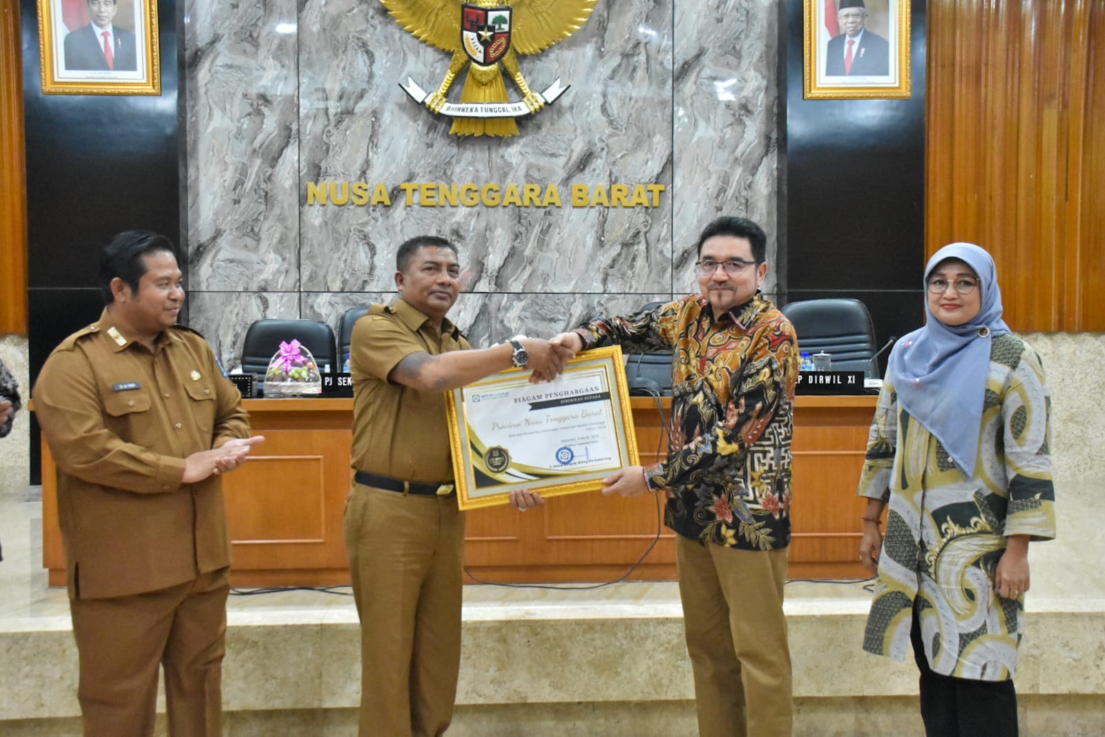 Pj Sekda NTB Ibnu Salim (dua dari kiri) saat menerima piagam penghargaan atas komitmen pemerintah daerah, untuk mencapai UHC Tahun 2024, yang diberikan BPJS Kesehatan Pusat, di Mataram, Senin (4/3).
