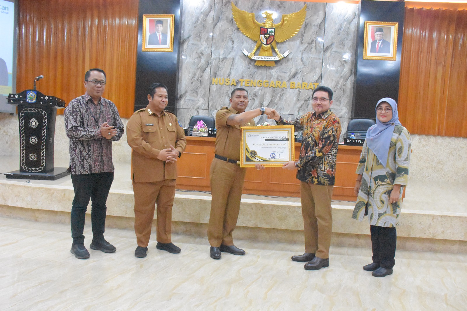 Direktur BPJS Kesehatan Mahlil Ruby (dua dari kanan) menyerahkan piagam penghargaan kepada Penjabat Sekda NTB Ibnu Salim didampingi Kepala Dikes NTB HL Hamzi Fikri di Gedung Sangkareang Kantor Gubernu