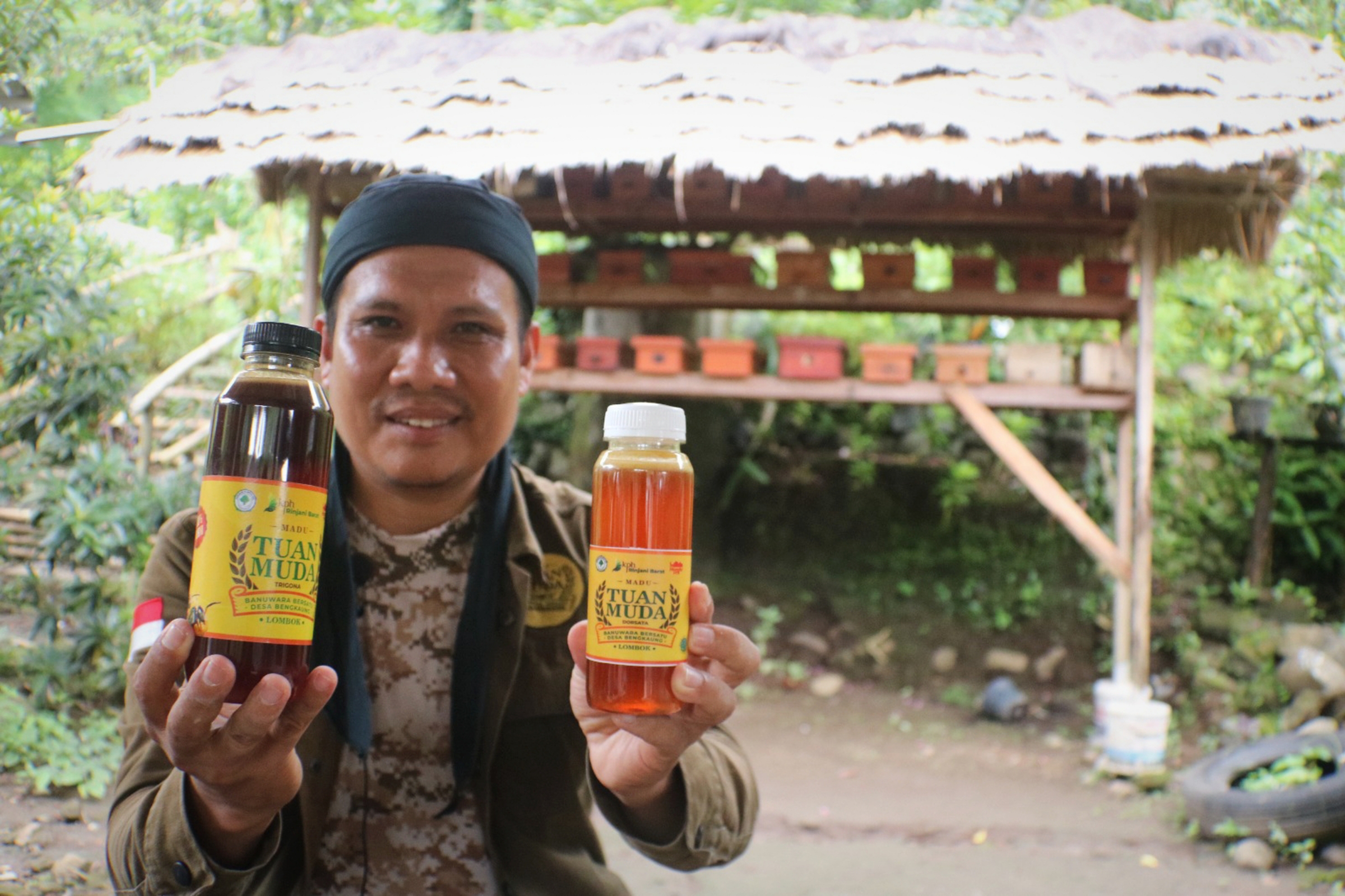 BISNIS MENGGIURKAN: Imamul Azkar menunjukkan dua botol produk madu trigona miliknya dengan merek Madu Tuan Muda.  (FERIAL/LOMBOK POST)