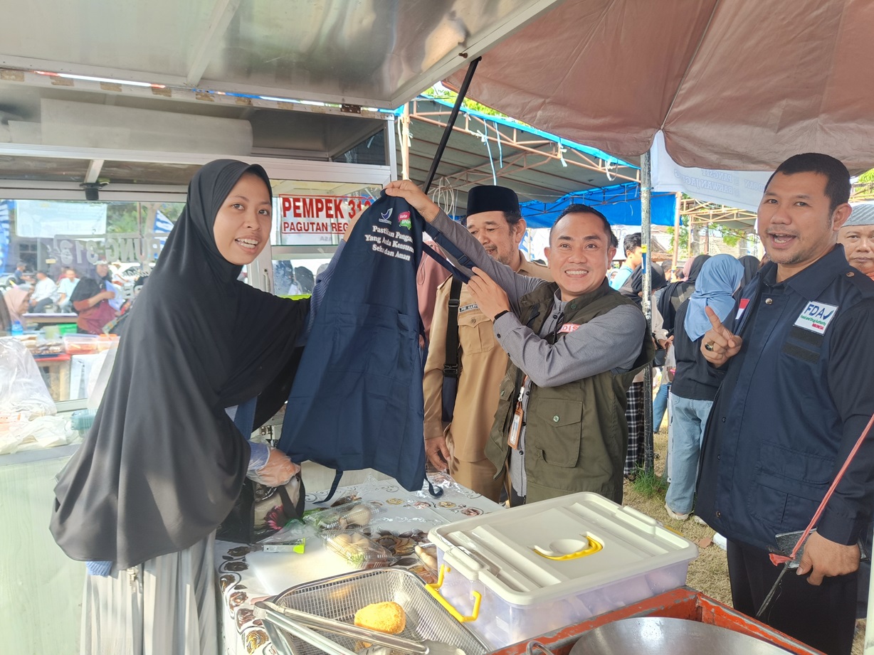 SIMBOLIK: Kepala Dinas Kesehatan Kota Mataram dr Emirald Isfihan secara simbolik menyerahkan celemek pada Dita, salah satu pedagang di sentra kuliner Pagutan Permai bersama Kepala BBPOM Mataram Yosef.