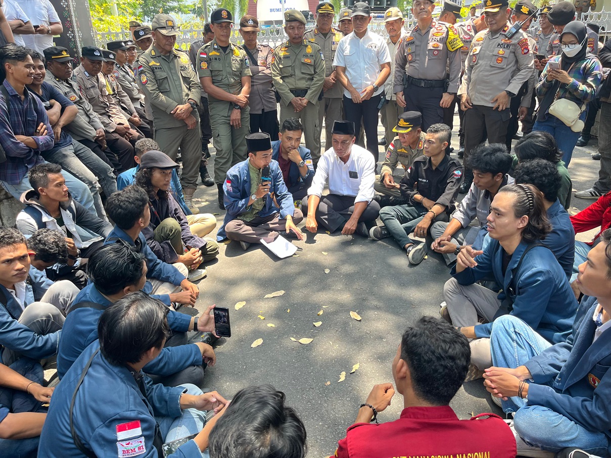 DENGAR ASPIRASI: Asisten III Setda NTB H Wirawan Ahmad (kemeja putih), sambil duduk berdialog bersama raturan mahasiswa yang menuntut aspirasi turunkan harga bapok, di depan Kantor Gubernur NTB.