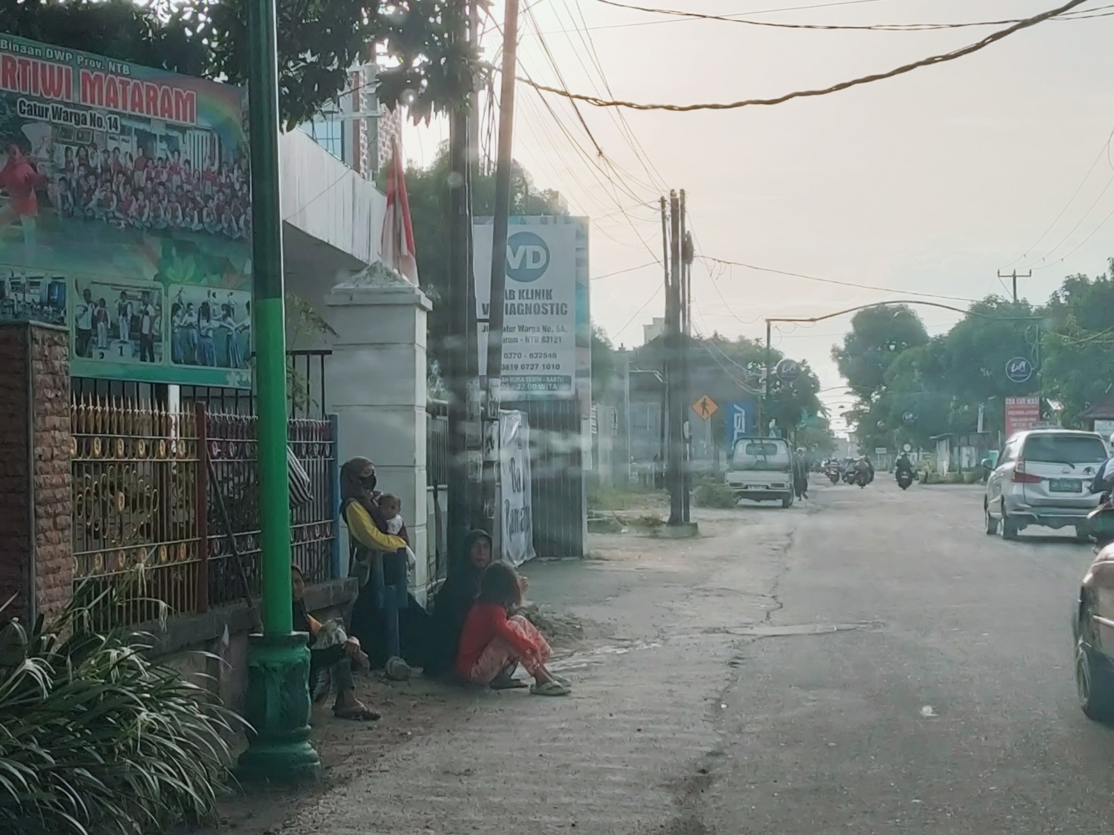 JALAN AKAN DIPERLEBAR: Sejumlah masyarakat duduk di depan salah satu lahan yang belum dibebaskan Pemkot Mataram di Jalan Catur, Minggu (24/3).