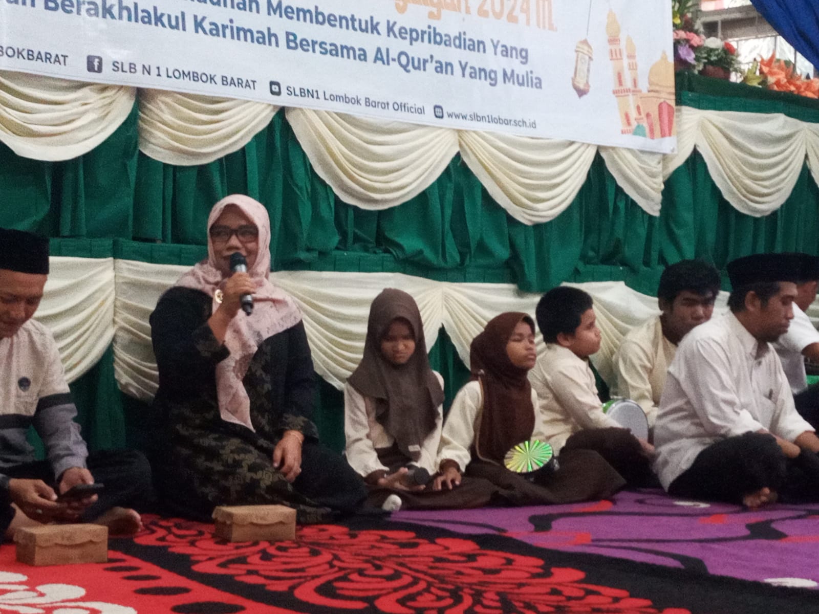 SAMBUTAN: Kepala SLBN 1 Lobar Baiq Minarniwati (pegang mik) memberikan sambutan pada acara Nuluzul Quran yang digelar di sekolah setempat, Kamis (28/3) lalu. (ROJAI/LOMBOK POST)