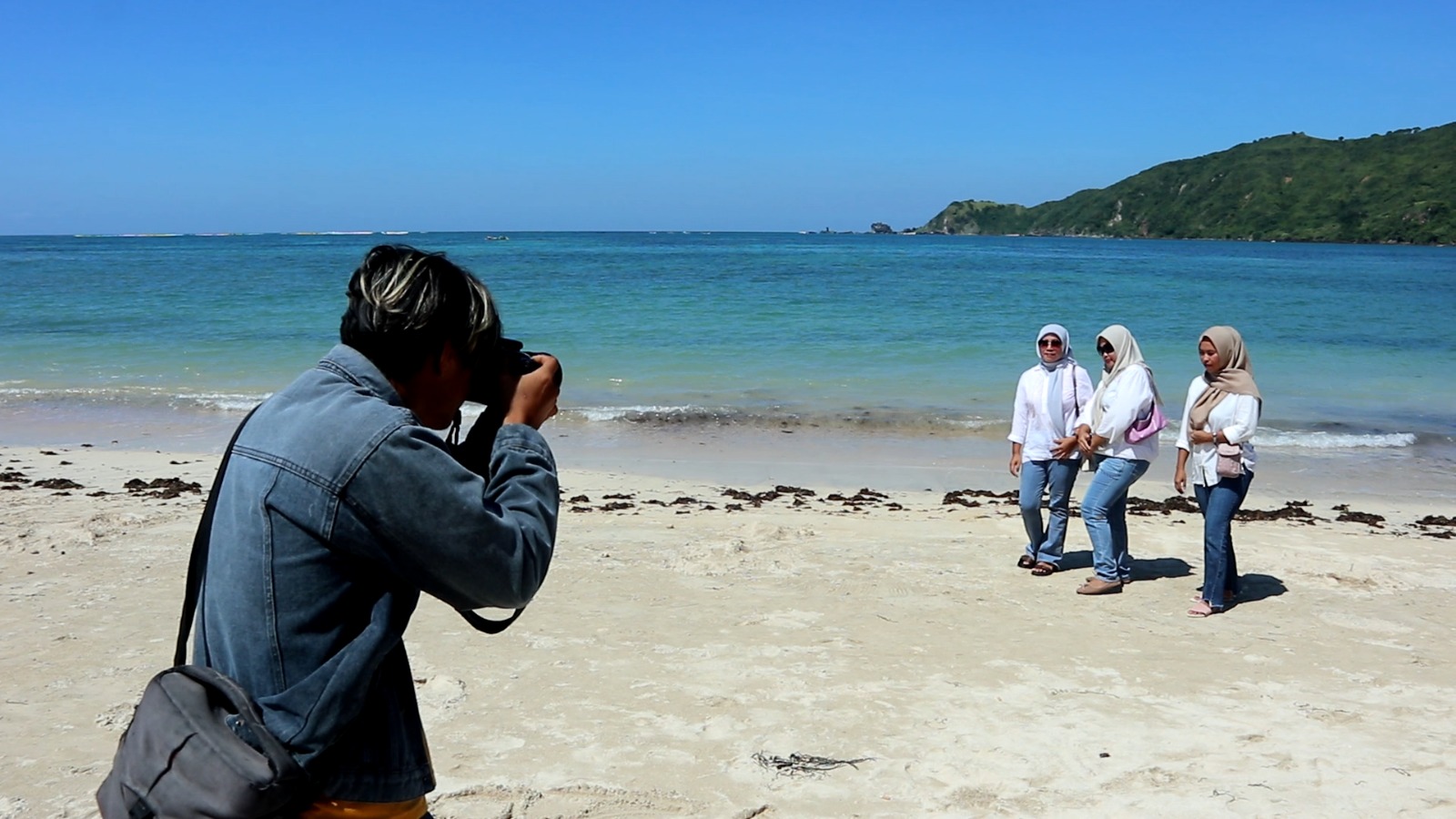 RAUP CUAN: Lalu Muhammad Zilatul Umar mengabadikan foto para wisatawan lokal dengan latar Pantai Kuta Mandalika, Loteng,&nbsp;Senin (15/4). (FOTO: Dewi/Lombok Post)