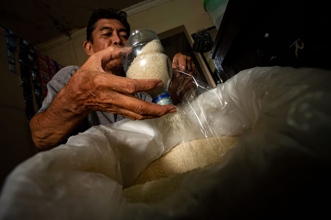 TAKARAN: Seorang pedagang memasukan gula pasir dalam plastik.