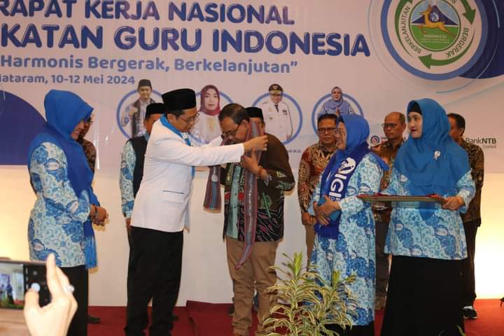 RAKERNAS: Ketua Umum IGI Danang Hidayatullah mengalungkan selendang kepada Kadis Dikbud NTB H Aidy Furqan pada pembukaan Rakernas di Same Hotel, Kota Mataram, kemarin (11/5).