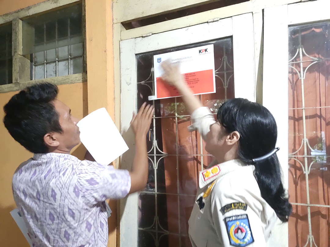 SELAMATKAN ASET DAERAH: Petugas Satpol PP menempelkan stiker tanda tanah milik Pemkot Mataram yang dibawa KPK, beberap waktu lalu.