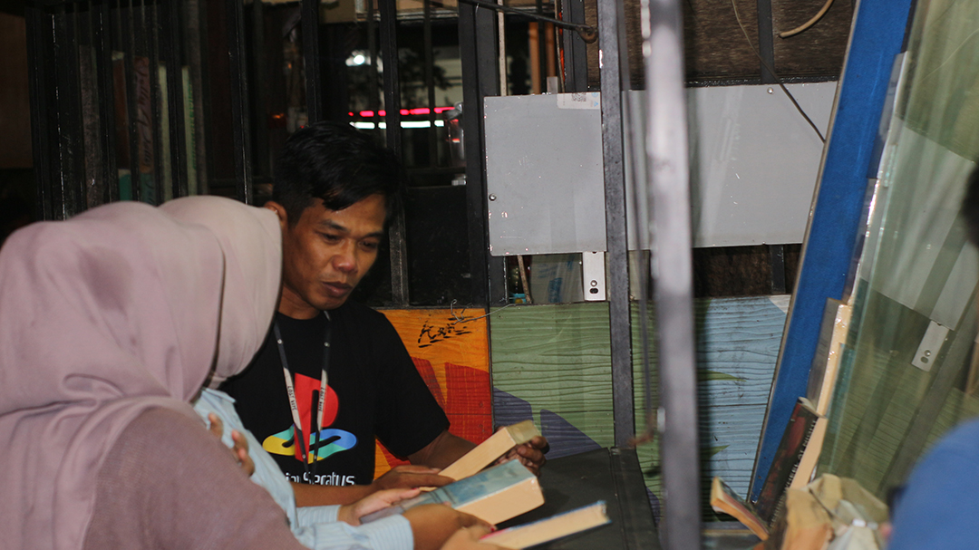 JUAL: Qori&rsquo; Bayinaturrosi pemilik lapak infinity book saat memperlihatkan buku di etalase miliknya kepada dua orang pembeli di salah satu kafe di Selong.(SUPARDI/LOMBOK POST)