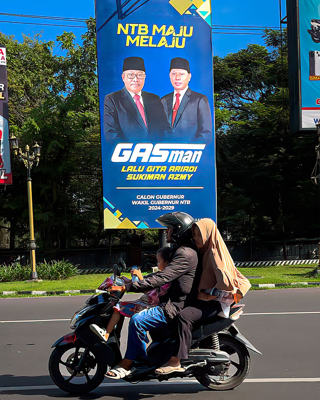 KEINGINAN JADI DEFINITIF: Warga melintas di depan baliho yang menampilkan Pj Gubernur NTB Lalu Gita Ariadi dan mantan Bupati Lotim HM Sukiman Azmy. (IVAN/LOMBOK POST )