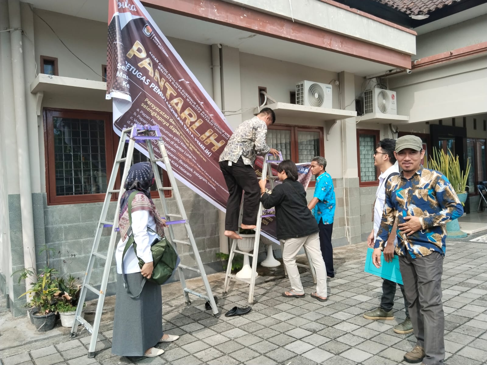 BUKA PENDAFTARAN: Komisioner KPU Kota Mataram Muslih Syuaib saat memantau pemasangan spanduk pendaftaran Pantarlih oleh KPU Kota Mataram, kemarin (13/6). (ZAD/LOMBOK POST )