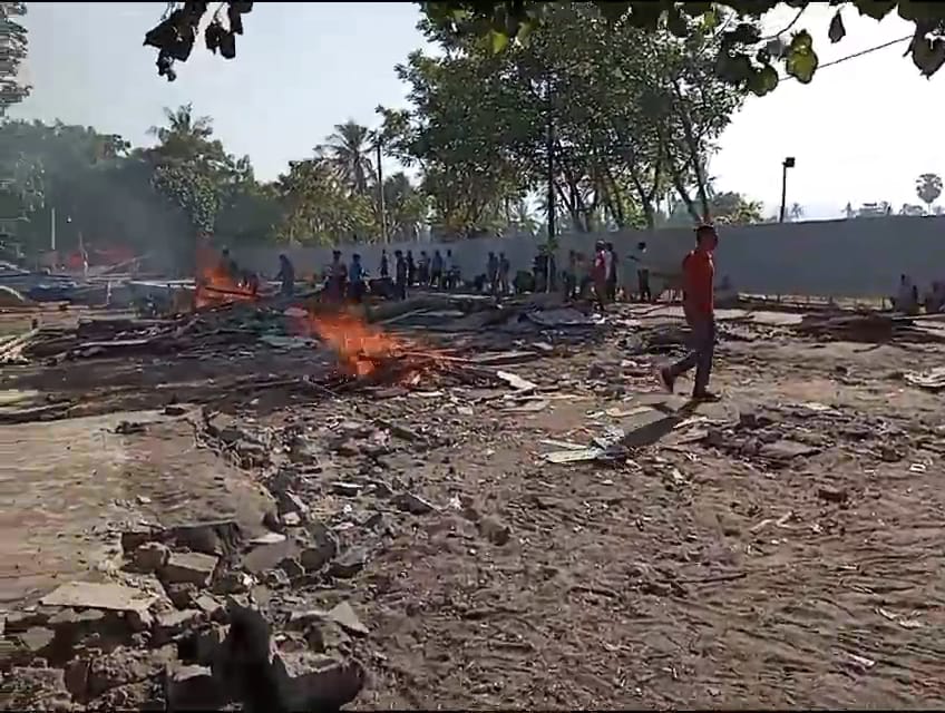 Lapak semi permanen milik Inaq Sur, dibersihkan oleh warga dengan cara dibakar. Bongkahan semen pun rencananya akan dipindahkan warga ke lokasi pembuangan.