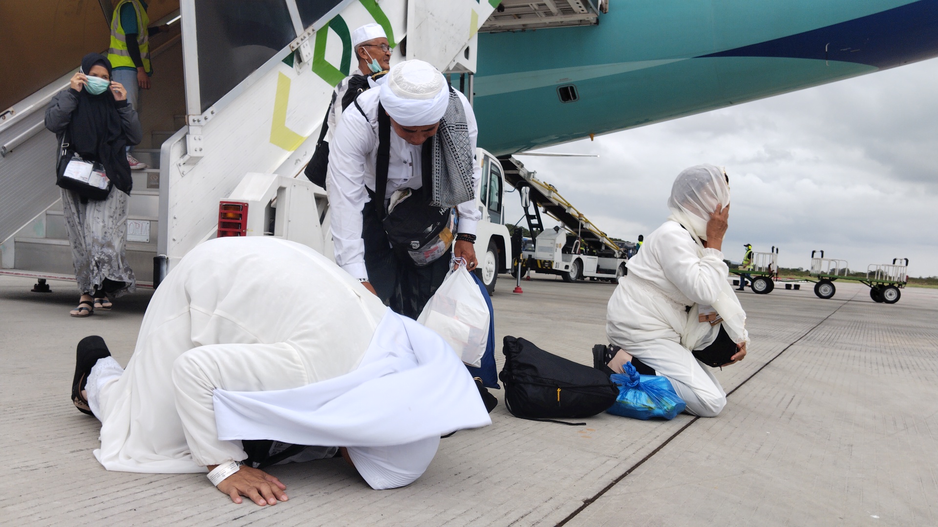 BERSYUKUR: Jamaah haji kloter 02 asal Loteng sujud syukur di apron Bandara Internasional Zainuddin Abdul Madjid, kemarin (24/6). (Dewi/Lombok Post)